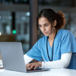 Orthopedic healthcare professional analyzing data on a laptop in a modern office setting